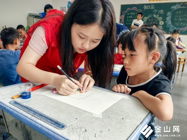 圖為團(tuán)隊(duì)成員和小朋友一起勾勒蠟染底稿